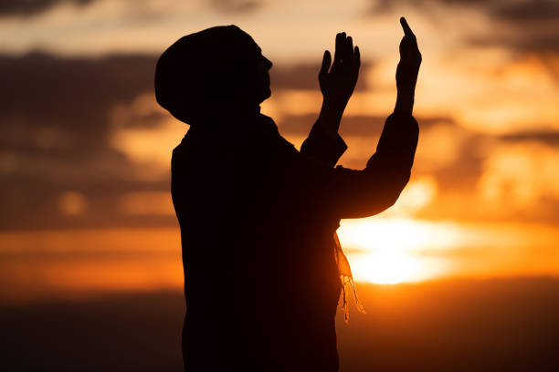 Muslim woman prayer having worship and praying with hands open doing dua to Allah at sunset Silhouette of muslim woman prayer having worship and praying with hands open doing dua to Allah at sunset . High quality photo i love allah in arabic silhouettes stock pictures, royalty-free photos & images