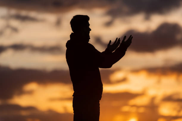 Silhouette of prayer having worship and praying with hands open at sunset Silhouette of muslim woman prayer having worship and praying with hands open doing dua to Allah at sunset . High quality photo i love allah in arabic silhouettes stock pictures, royalty-free photos & images