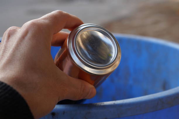 istock Close-up of a white man's hand throwing an aluminum can into a blue plastic garbage can. Collection of raw materials and disposal of waste from food and human activities and recycling 2192187254