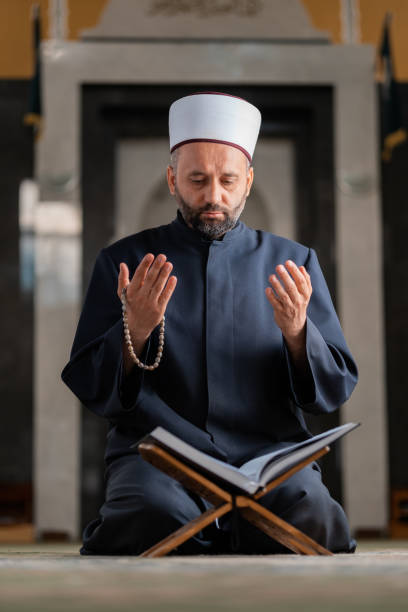 istock A Muslim prayer man praying with hands up while reading a Quran inside the mosque. 2192187655
