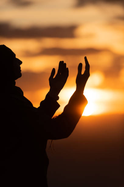 Silhouette of Muslim woman prayer having worship and praying with hands open doing dua to Allah at sunset concept of faith belief spiritual. Silhouette of muslim woman prayer having worship and praying with hands open doing dua to Allah at sunset . High quality photo i love allah in arabic silhouettes stock pictures, royalty-free photos & images