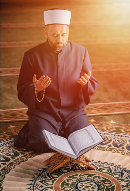 istock A Muslim prayer man praying with hands up while reading a Quran inside the mosque. 2192187767
