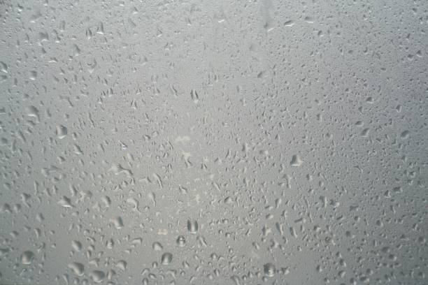 Water drops on grey glass surface, closeup