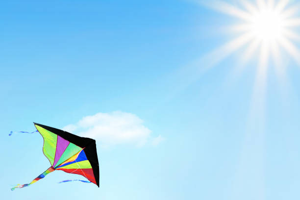 Multi colored kite flying in the blue sky with beautiful sunbeams. Space for copy.