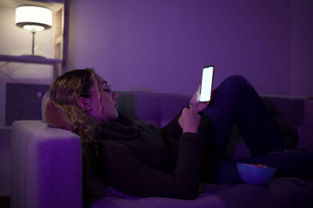istock Young woman relaxing on sofa using smartphone with blank screen in living room at night 2192191139