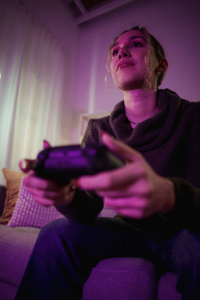 istock Young woman playing videogames on a sofa at home 2192191170