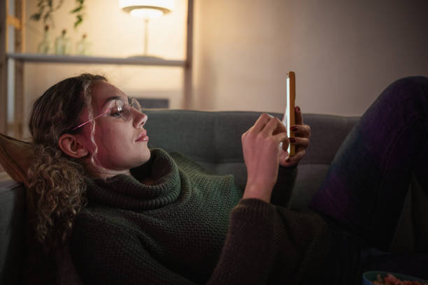 istock Young woman relaxing on sofa using smartphone at night 2192191173