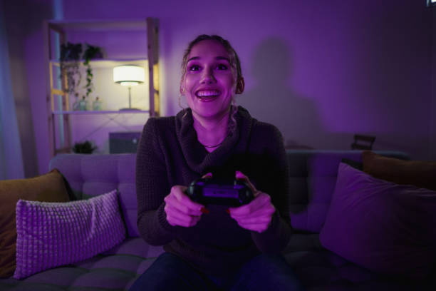 istock Excited young woman playing videogames on a sofa at home at night 2192191177