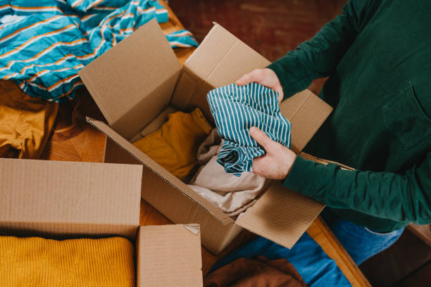 istock Unrecognizable man putting old clothes into box for charity or upcycling 2192191351
