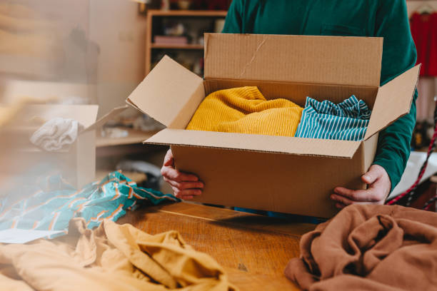 istock Unrecognizable man putting old clothes into box for charity or upcycling 2192191352