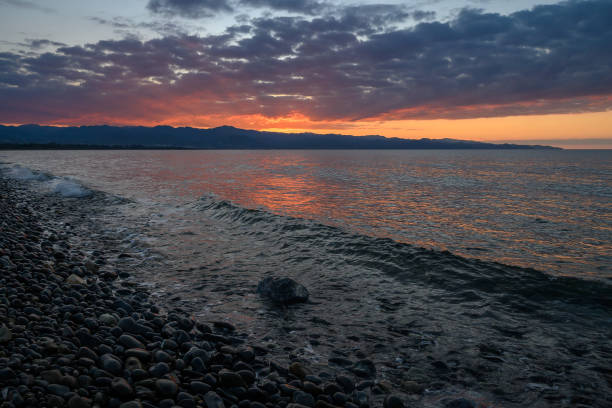 istock Mesmerizing sunset reflections over calm waters by the rocky shoreline in a tranquil coastal setting 2192192058