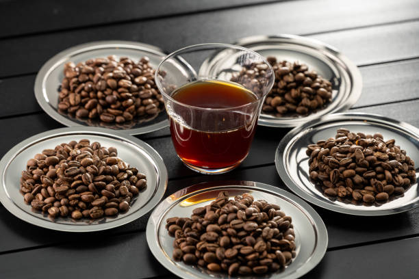 cup of coffee and coffee beans on black background with light passing through