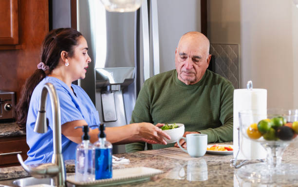 istock Hispanic home caregiver with senior man in kitchen 2192198428