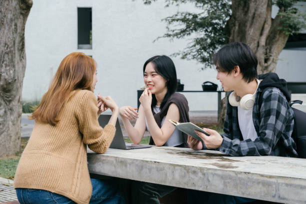 istock Three young adult university students are actively engaged in a collaborative project, utilizing a laptop and notebook while sitting at an outdoor table, fostering teamwork and knowledge sharing 2192205961