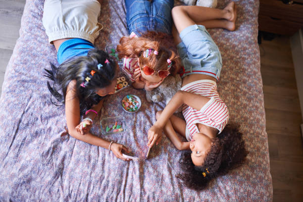 istock Sweet Moments: Girls Sharing Treats on Bed 2192218130