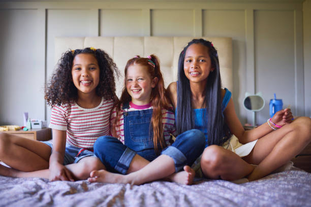 istock Three Happy Friends Sitting on Bed 2192218158