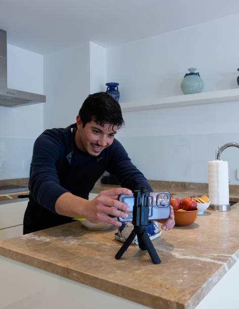 istock Vertical image of young man organizing his cell phone to start recording a tutorial of a dessert recipe at home 2192224980