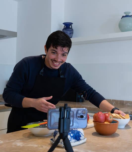 istock Vertical image of a young man showing the ingredients making a tutorial on how to cook a dessert at home 2192224988