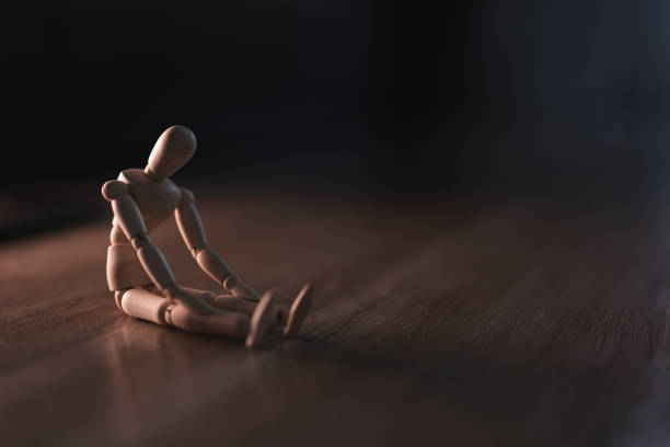 istock Wooden doll sits sadly and alone on the floor 2192226661