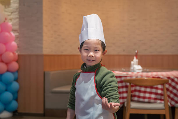 A close-up of a young boy with the chef cap smiling at the camera