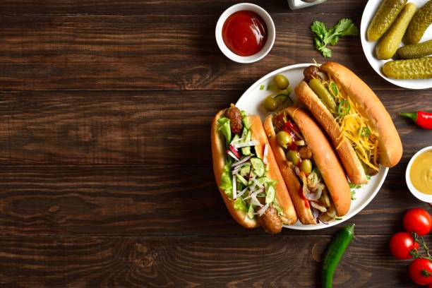 Hot dogs loaded with assorted toppings on wooden background