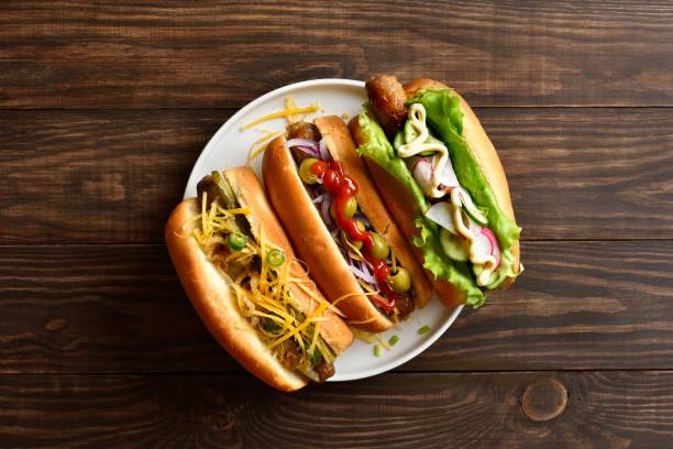 istock Hot dogs loaded with assorted toppings on wooden background 2192228627