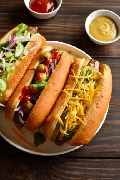 istock Hot dogs loaded with assorted toppings on wooden table 2192228628