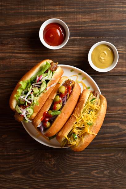 istock Hot dogs loaded with assorted toppings on wooden background 2192228633