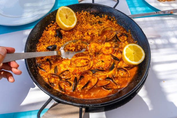 istock Spoon taking seafood paella directly from paella pan with lemon wedges 2192228773