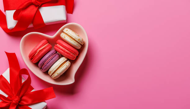 istock Colorful macaroons elegantly arranged in a heart-shaped bowl, paired with a charming Valentines Day gift boxes 2192228927