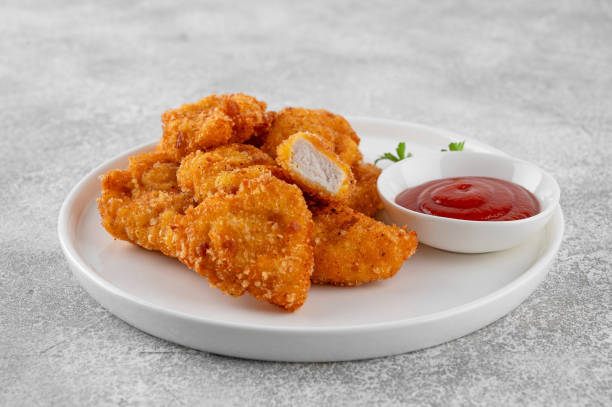 istock Crispy chicken nuggets with ketchup on a white plate on a gray concrete background. 2192229426