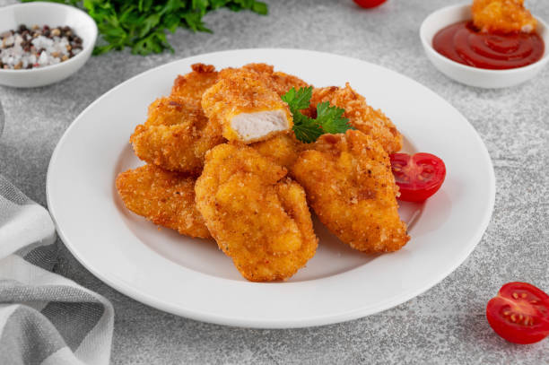 istock Crispy chicken nuggets with ketchup on a white plate on a gray concrete background. 2192229429