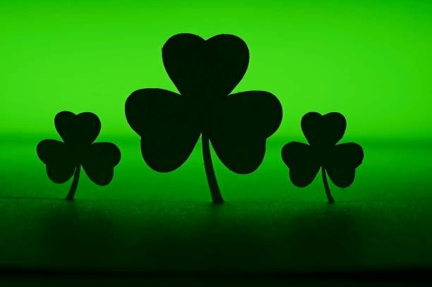 Three shamrock silhouettes on a green background