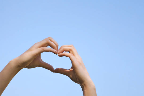 istock heart shape hand sign or love gesture against clear blue sky 2192230485