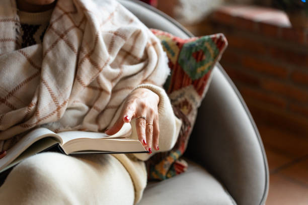 istock Close-up of a married woman's hand reading a book while sitting on a sofa 2192230644
