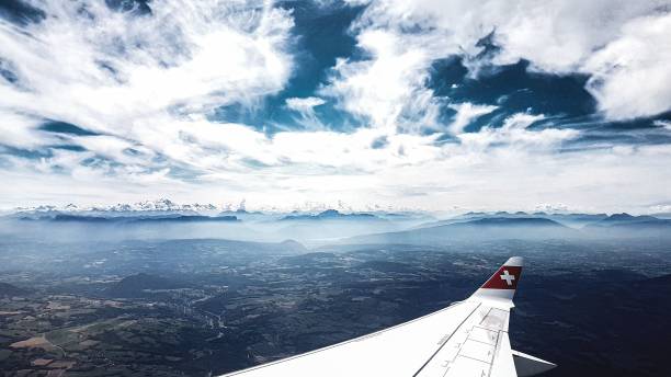 Zurich, Switzerland – June 10, 2024: A lone hiker stands on a snow-covered mountain summit under a dramatic sky.