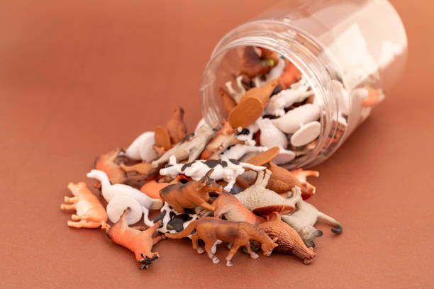 istock Miniature plastic toy animals spilled out from a transparent container on a brown background 2192232693