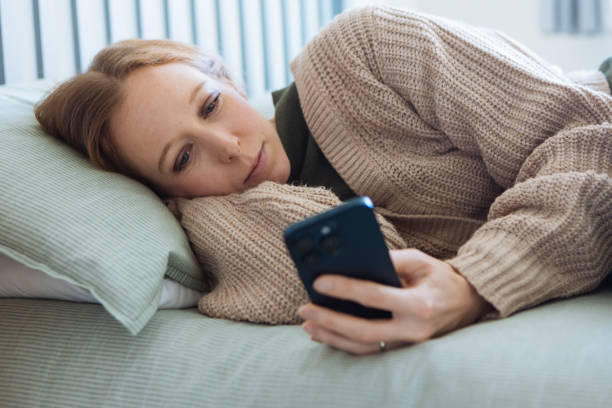 istock Beautiful woman using a smartphone on bed 2192233057