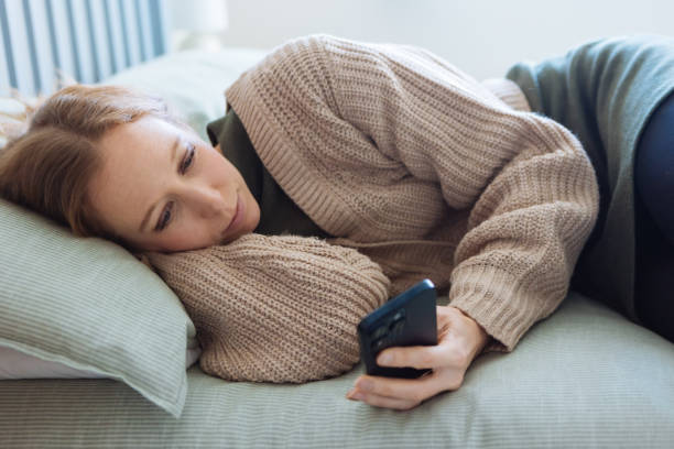 istock Beautiful woman using a smartphone on bed 2192233074