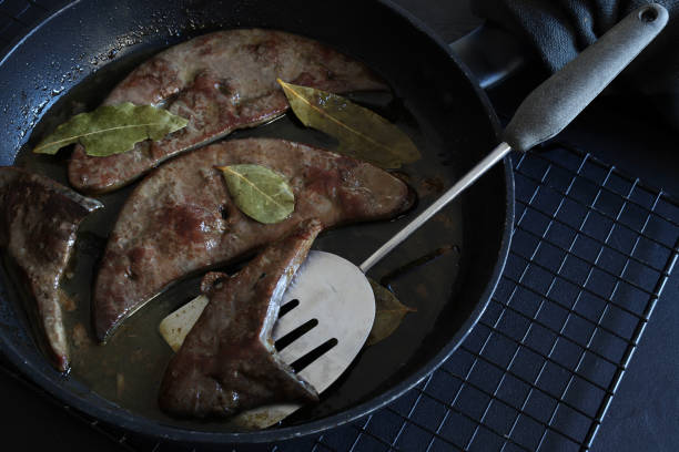 Delicious fried veal liver pieces in a frying pan on dark background. Directly above.