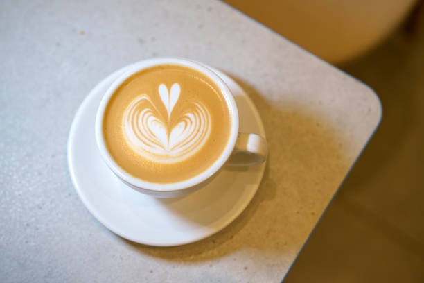 A top-down view of a beautifully crafted latte with heart-shaped latte art, served in a white ceramic cup.