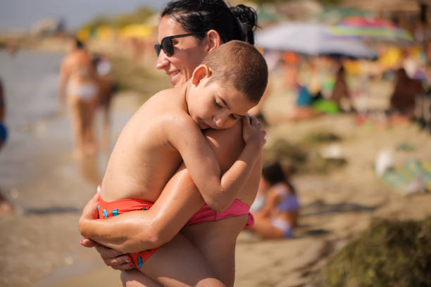 A mom with her arms around her child with special needs, spending quality time by the shore.
