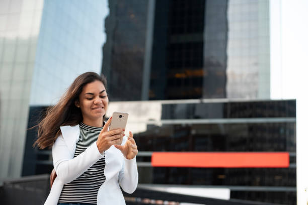 istock Woman using smartphone and smiling in front of building 2192239754
