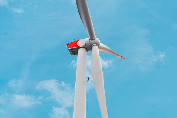 istock Wind Turbine Under Operational Maintenance by a Windtech Technician Climbing Up the Windmill Alongsinde the Rotor Blade to Inspect and Repair The Parts 2192251282