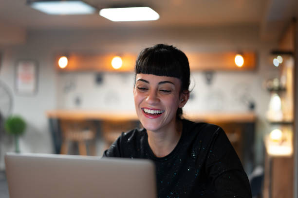 istock Young woman laughing while working on laptop in a cafe 2192252774