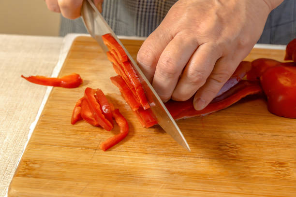 istock Cook cuts sweet red pepper into small pieces on a cutting board. Close-up 2192255565