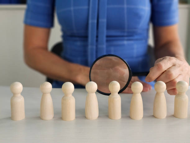 istock Searching for missing person in crowd of toy human figures with magnifying glass 2192257544