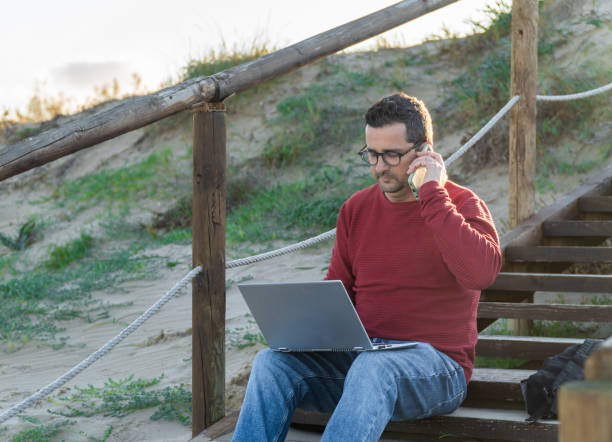 istock A man digital nomad working on a laptop and taking voice notes on the phone 2192260460