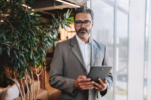 istock Businessman looking at camera holding digital tablet 2192261128
