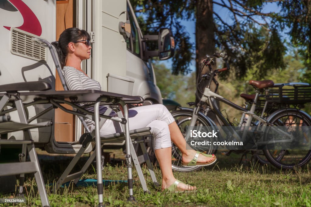 Woman resting near motorhomes in nature. Family vacation travel, holiday trip in motorhome RV, Caravan car Vacation. - Foto de stock de A caminho royalty-free Woman resting near motorhomes in nature. Family vacation travel, holiday trip in motorhome RV, Caravan car Vacation. - Foto de stock de A caminho royalty-free